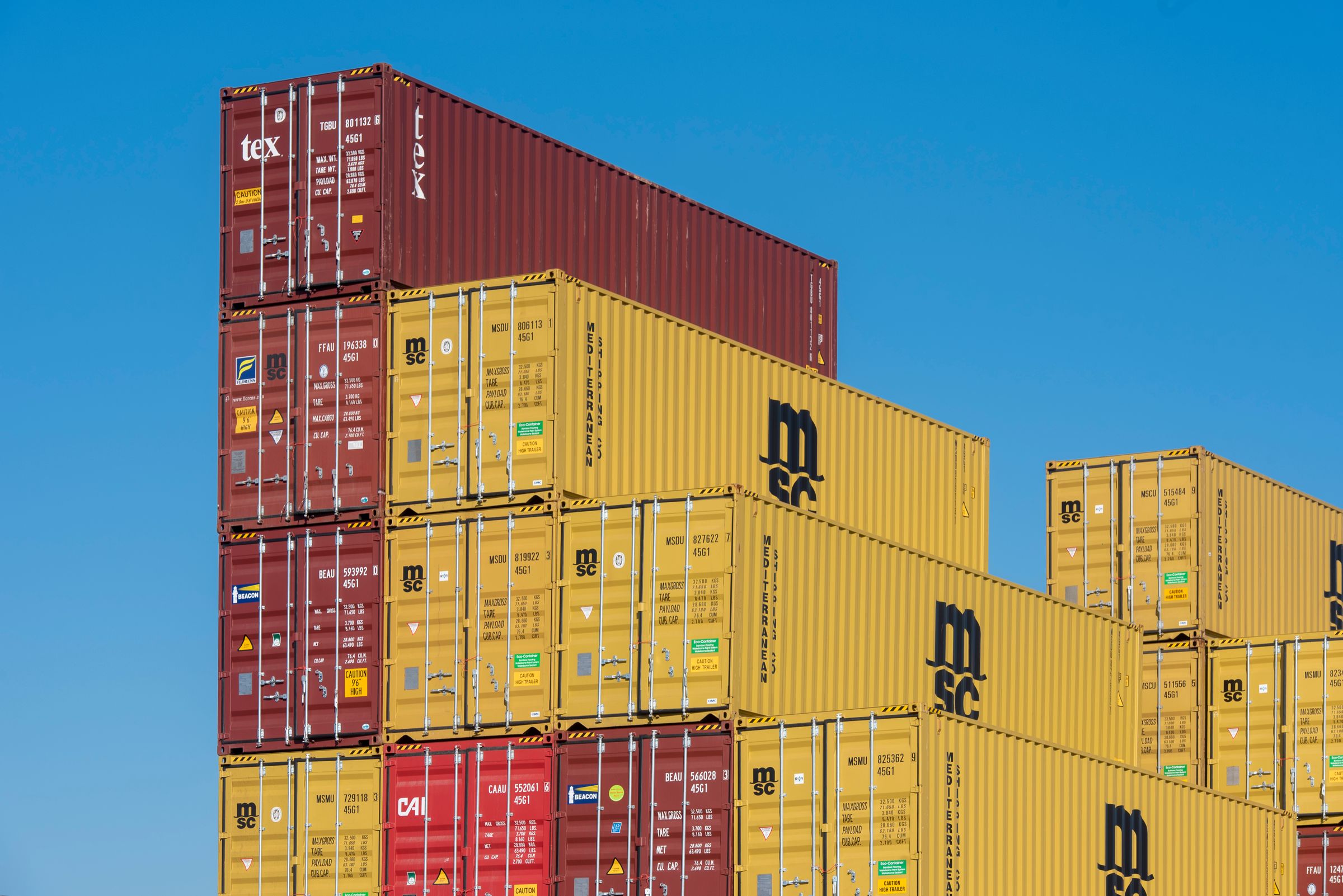 Stacked shipping containers against a bright blue sky